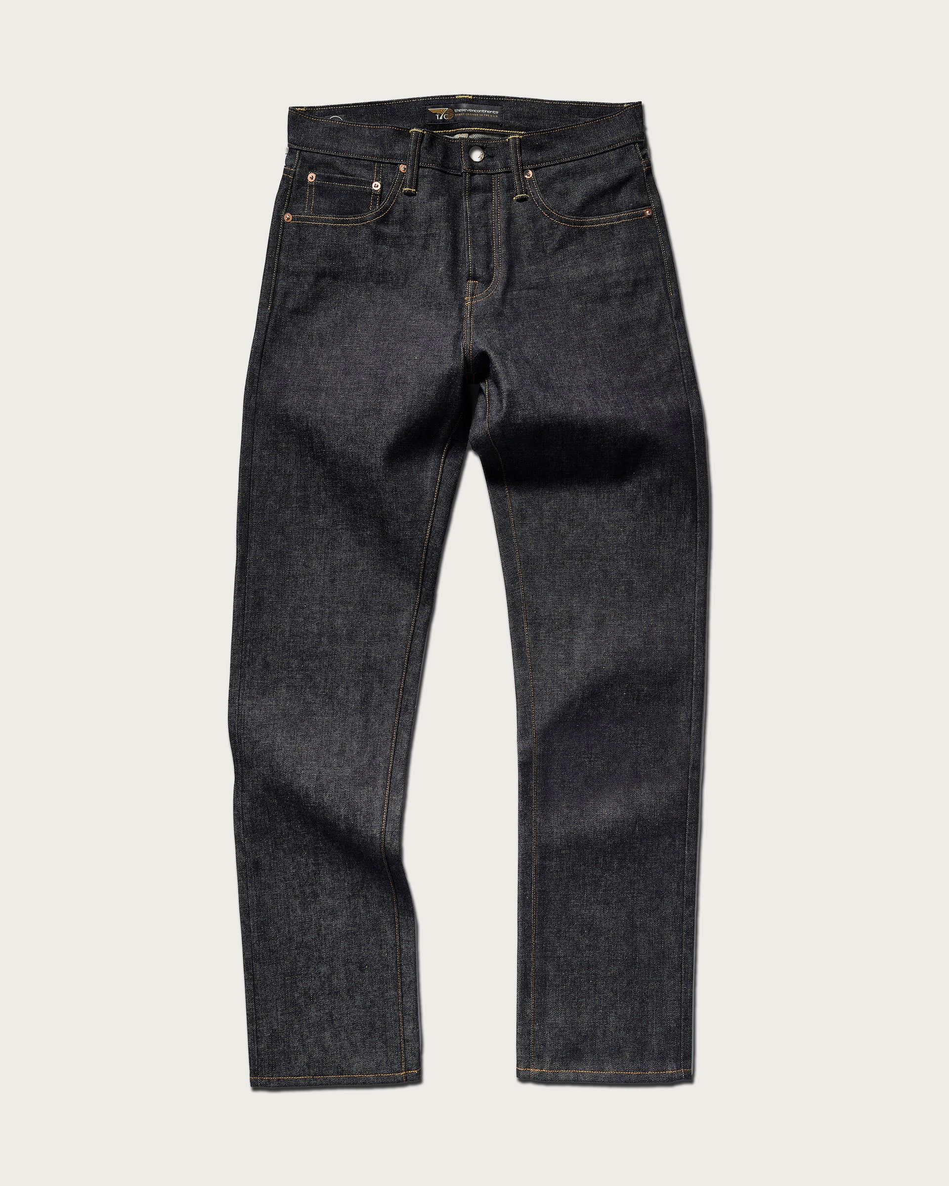 The Charlie in Yokohama Raw by T7C The Seven Continents: dark blue, indigo rope-dyed straight-leg jeans with a classic five-pocket design and orange stitching, shown laid flat on a light background.