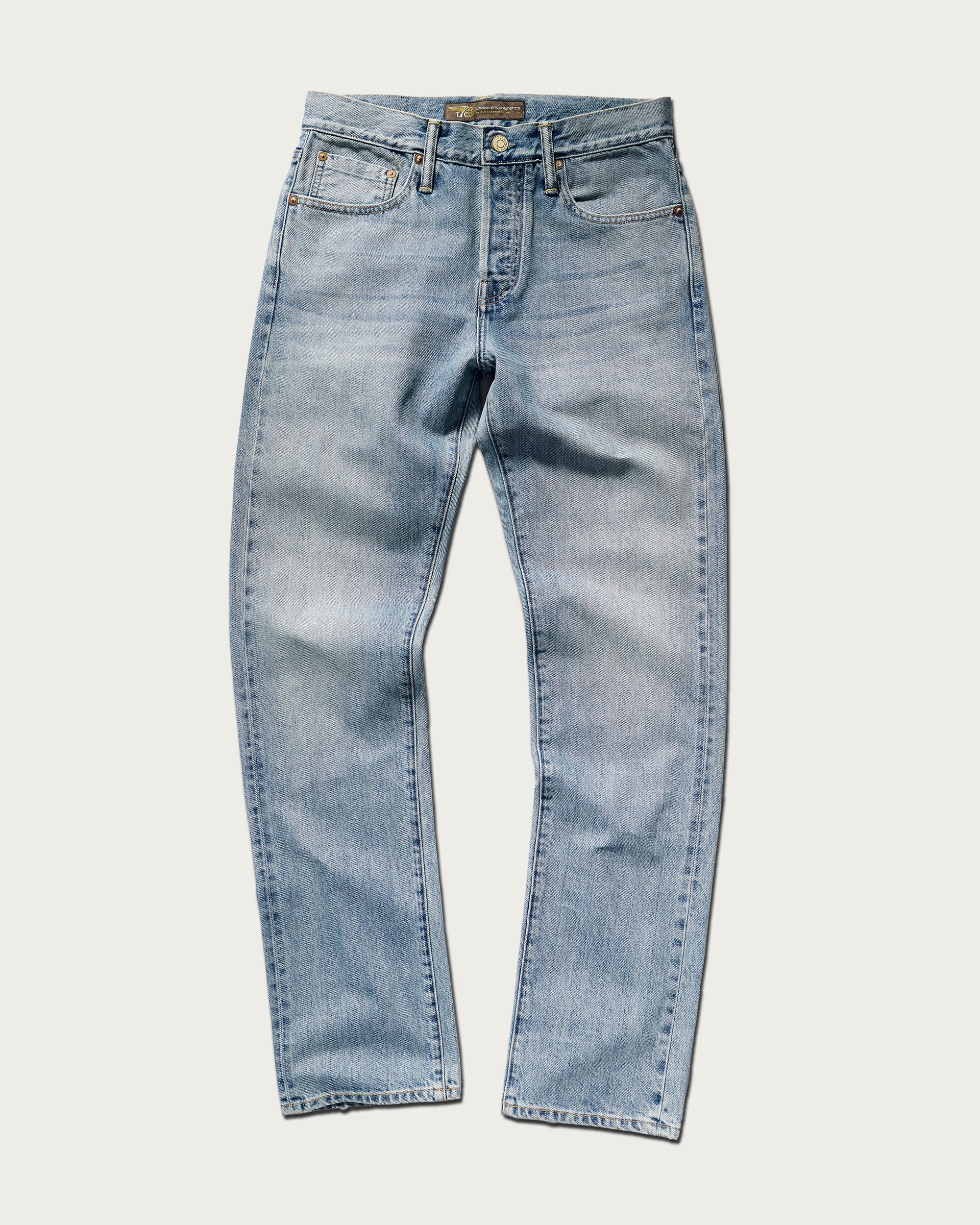 The Charlie Jean in Zuma by T7C The Seven Continents features light blue Japanese denim, a straight-leg fit, classic five-pocket style, button closure, and subtle front fading, shown against a white background.