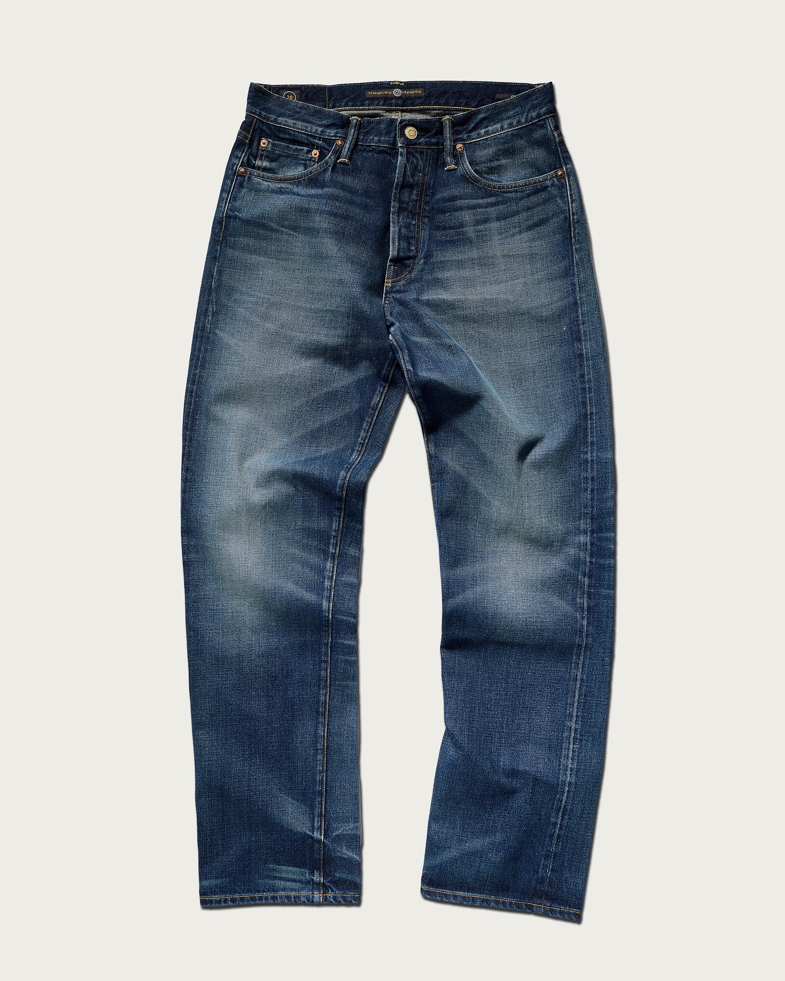 The Dylan Twisted Relaxed Jean in Nimes by T7C, shown flat on a light background, features blue Japanese denim with a faded, worn-in look, classic five-pocket styling, visible thigh whiskering, and shrink-to-fit construction.