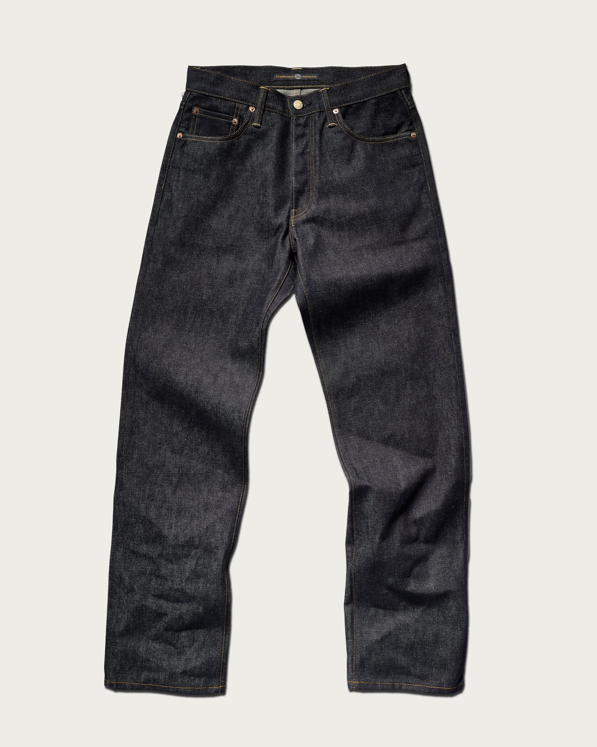 The Jack Jean In Yokohama Raw by T7C The Seven Continents—a pair of dark blue, rope-dyed indigo straight-leg jeans with a button fly, front and back pockets, and visible stitching—laid flat on a light background.