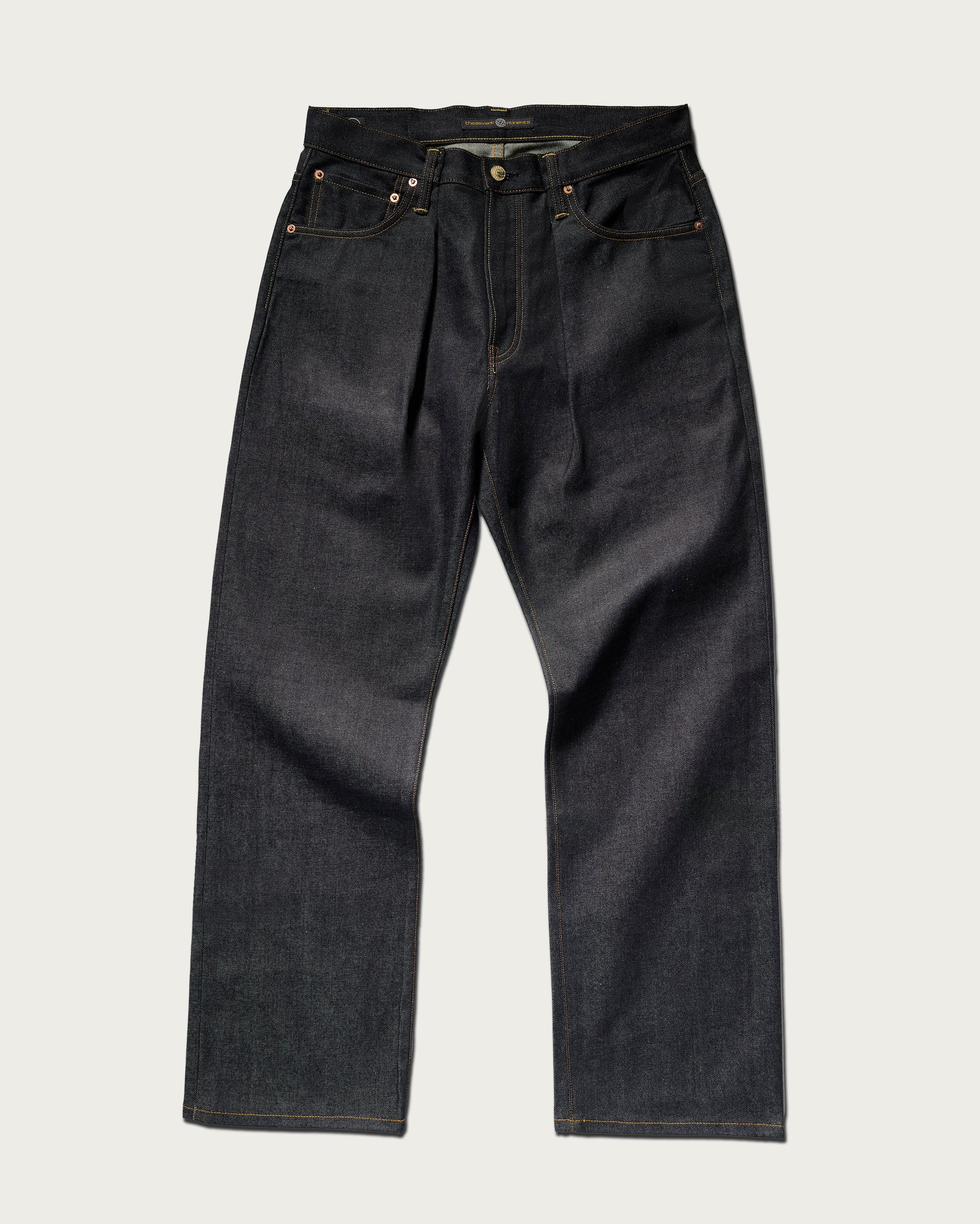 The Cinch Jean in Yokohama Raw by T7C The Seven Continents features straight-leg, indigo-dyed denim with five pockets, visible stitching, and metal rivets, shown laid flat on a light background.
