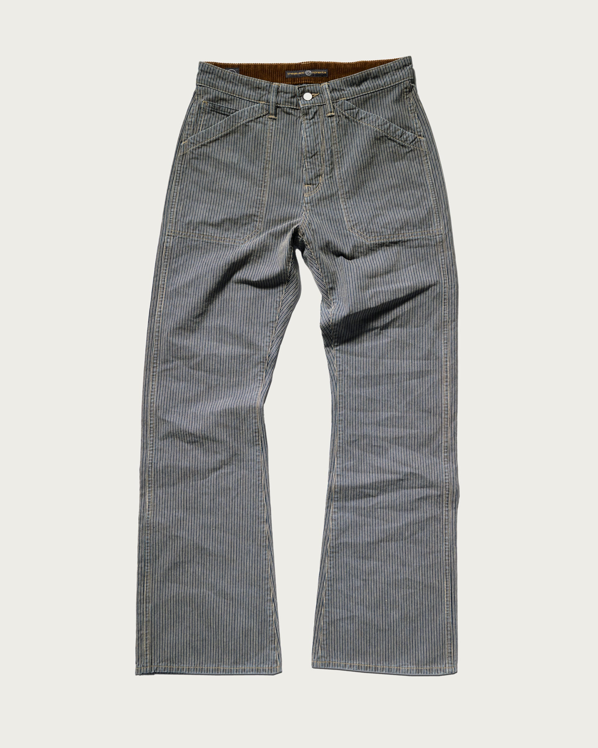 The Grayson Pant in Indigo Stripe by T7C The Seven Continents features blue and white railroad stripes, a button and zipper closure, front pockets, and straight legs, shown laid flat on a white background.