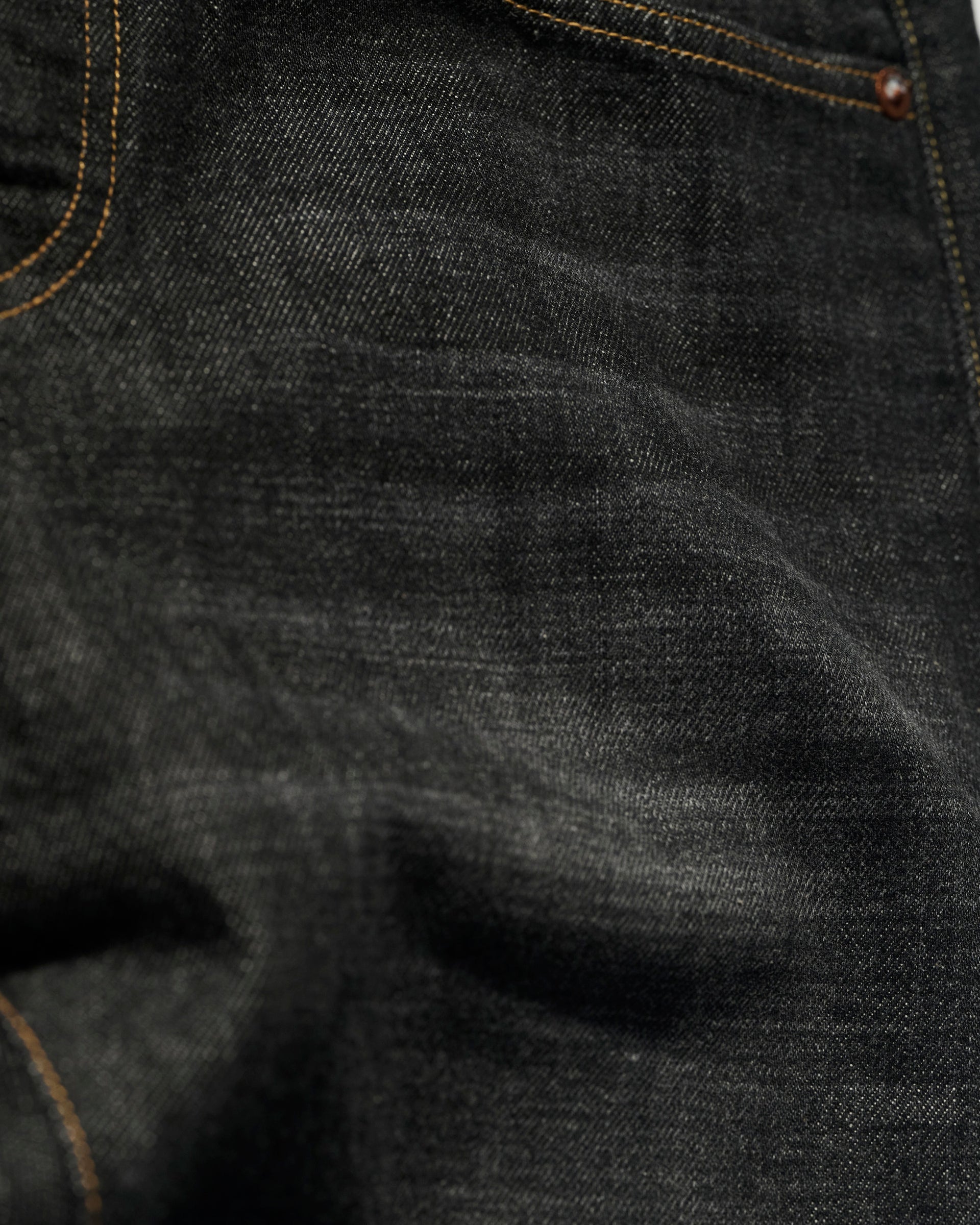 Close-up of The Charlie Jean in Fuji Black by T7C, made in LA from organic Turkish cotton, featuring dark blue denim texture, orange stitching, and a pocket with a metal rivet.