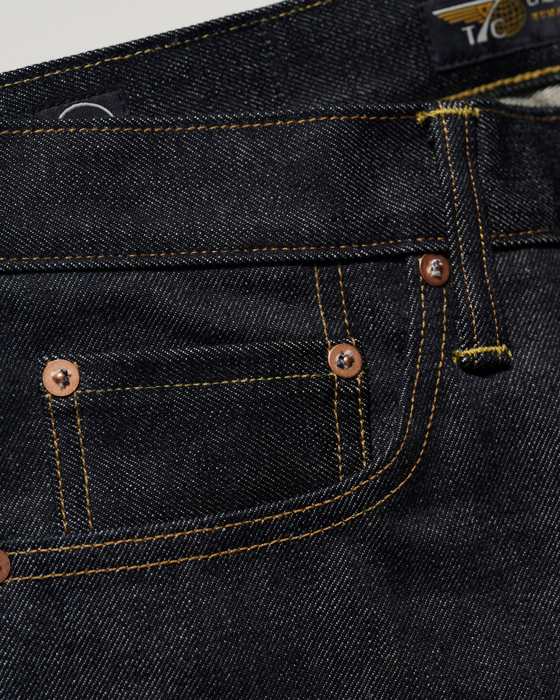 Close-up of The Charlie in Yokohama Raw by T7C The Seven Continents—slim fit jeans made from indigo rope-dyed Japanese selvedge denim, highlighting the front and coin pockets, copper rivets, and yellow stitching.