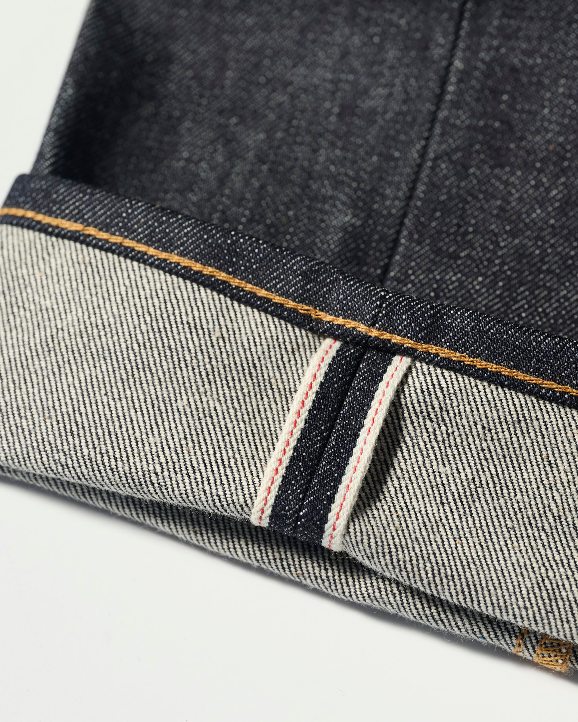Close-up of the cuff on T7C The Seven Continents’ The Charlie in Yokohama Raw jeans, highlighting the indigo Japanese selvedge denim, signature white and red edge, and contrast stitching.