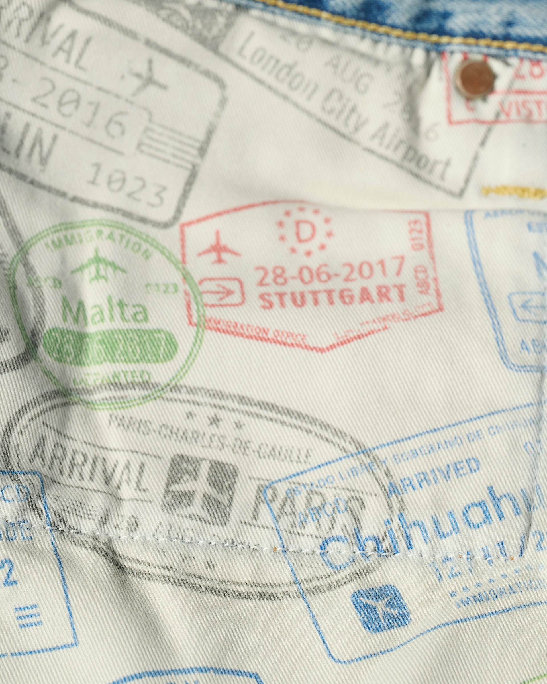 Close-up of The Charlie Jean in Zuma by T7C The Seven Continents, featuring colorful passport stamp prints and blue Japanese denim—ideal for travel-inspired style lovers and fans of premium slim fit jeans.