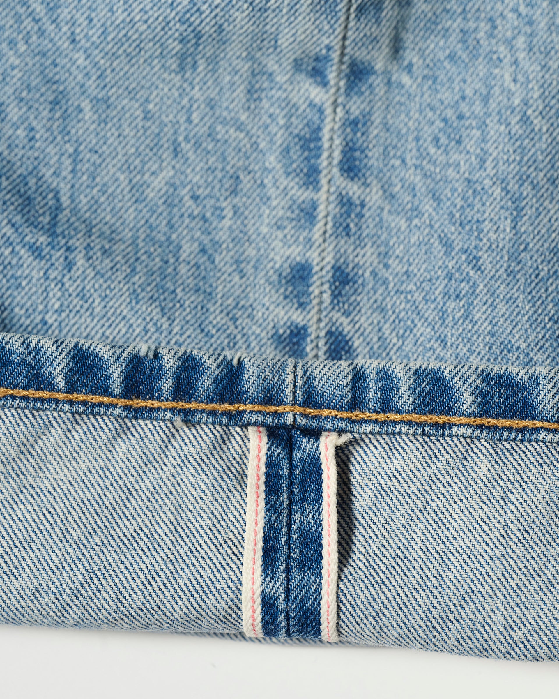 Close-up of the hem on T7Cs The Cinch Jean in Mykonos, featuring a folded cuff with visible stitching and a white selvedge edge with red stripe, showcasing vintage-inspired texture.