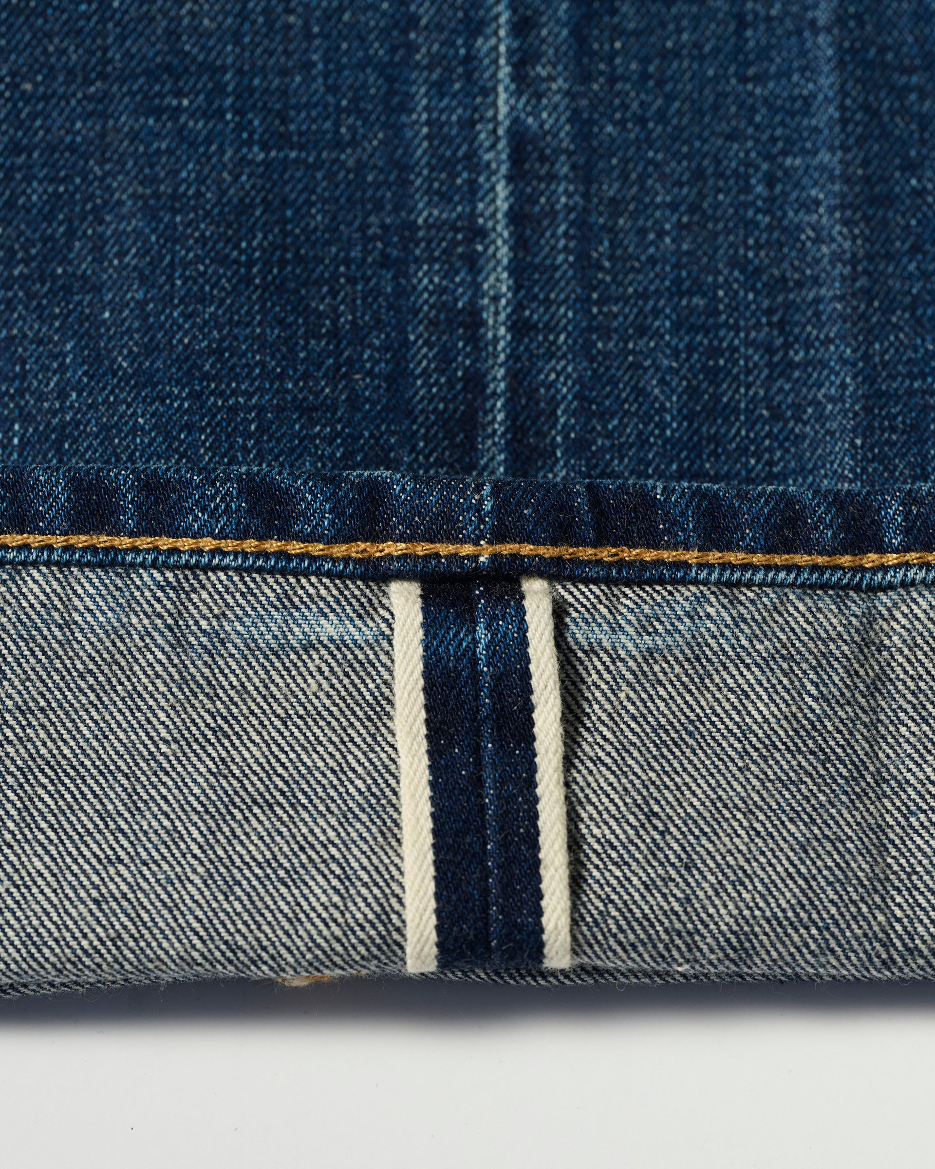 Close-up of the cuff on T7C’s The Dylan Twisted Relaxed Jean in Nimes, showcasing blue Japanese denim selvedge with a distinct white strip and blue stitching on the reverse side.