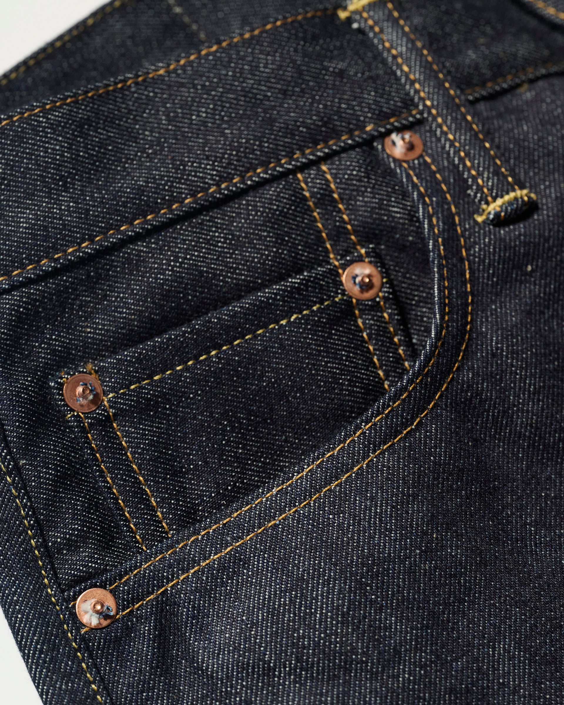 Close-up of the front and coin pockets on The Jack Jean In Yokohama Raw by T7C The Seven Continents, crafted from dark blue rope-dyed indigo denim with orange stitching and copper rivets.