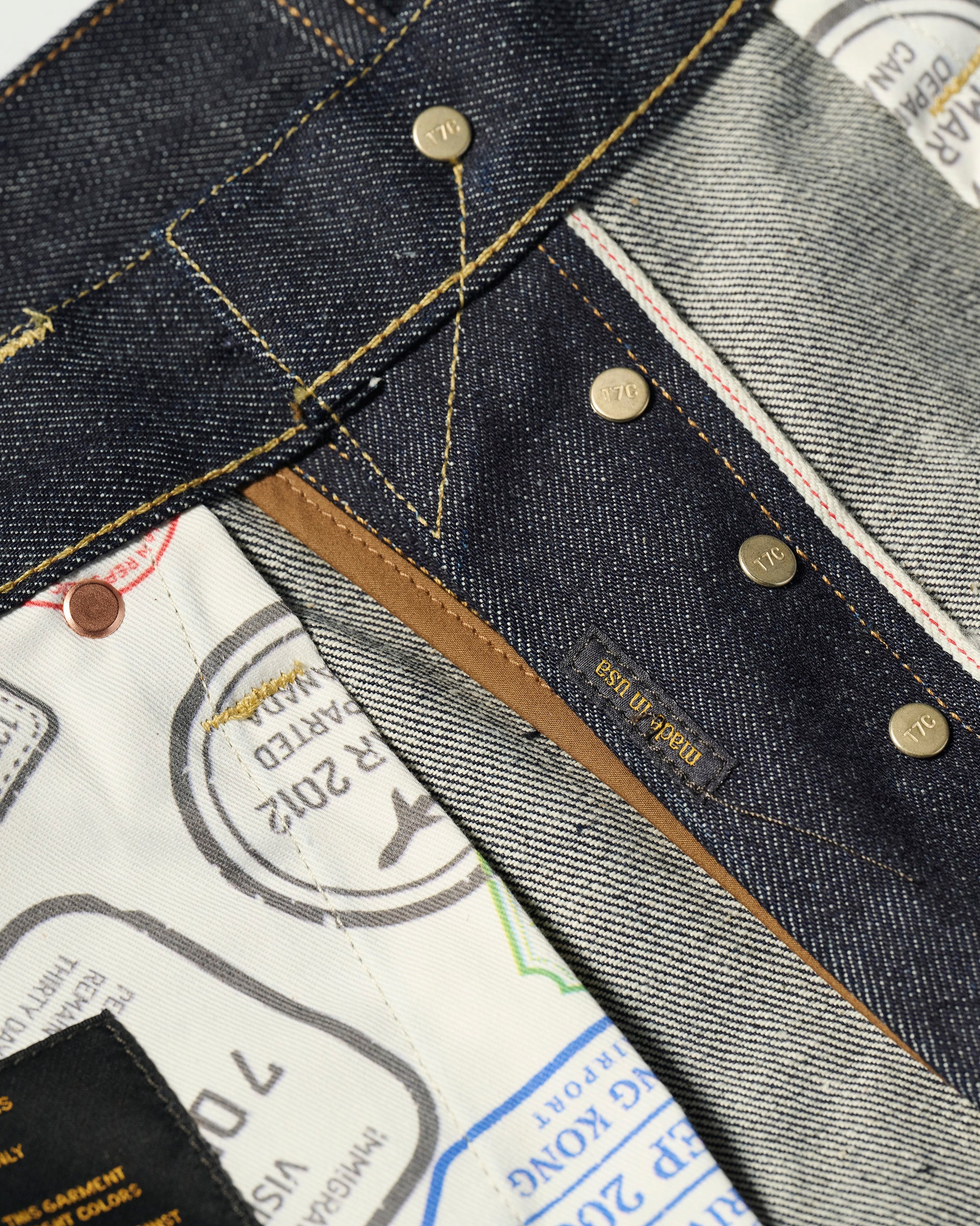 Close-up of The Jack Jean In Yokohama Raw by T7C The Seven Continents, featuring rope-dyed indigo Japanese denim, exposed stitching, metal rivets, and a pocket lining with colorful passport stamp designs.