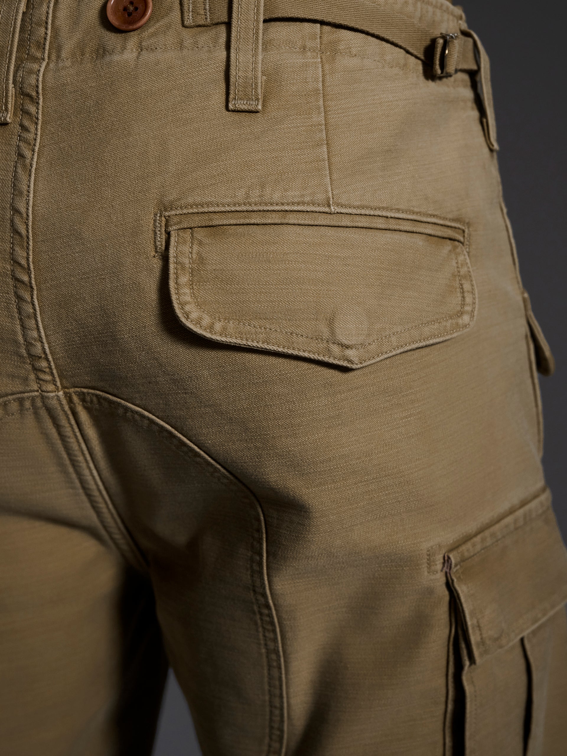 Close-up of the back pocket and side cargo pocket on The Brando Cargo in Sand by T7C, featuring detailed stitching, button, belt loop, and rich cotton-back satin texture from sulphur dyeing.