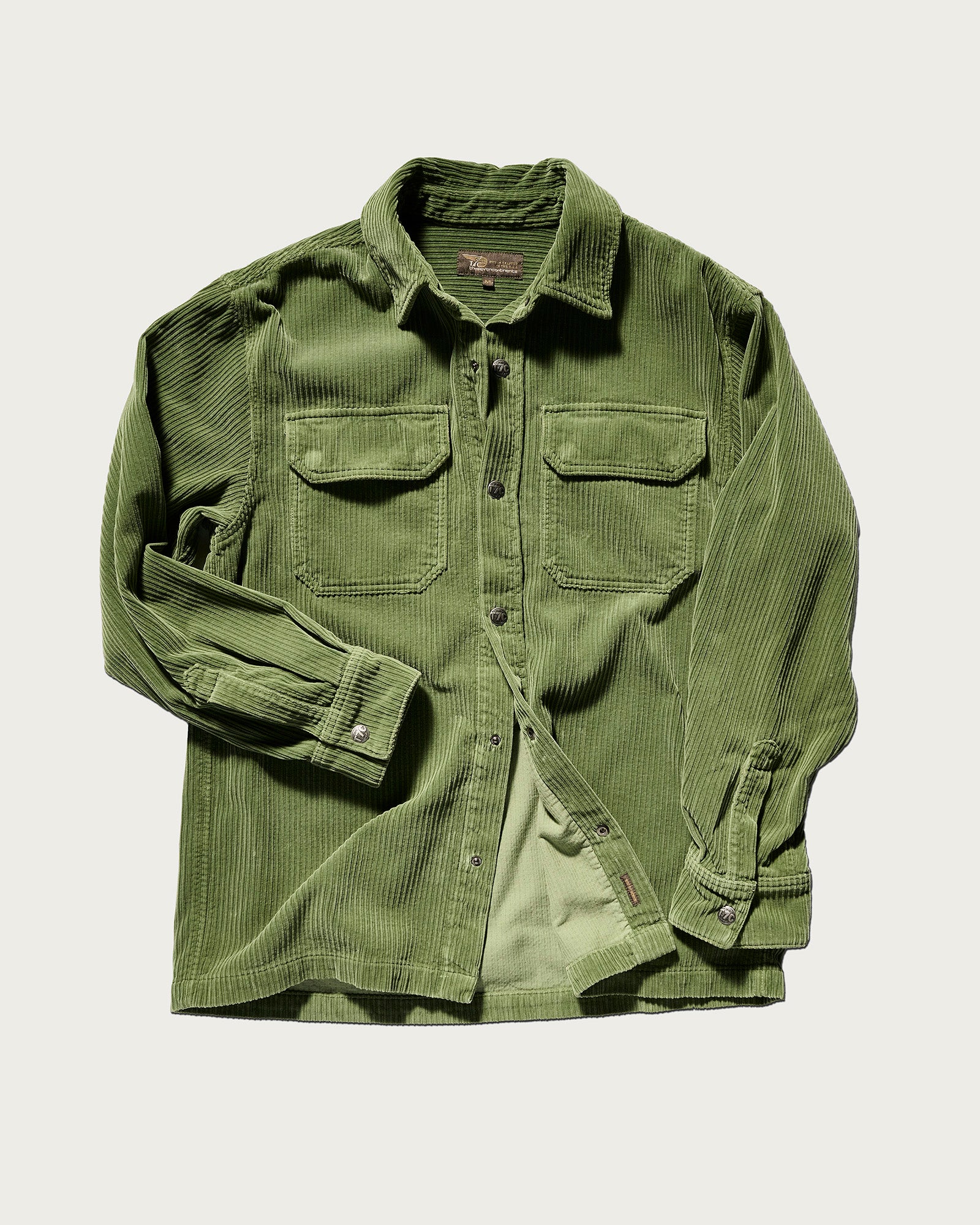 The T7C Aiden Overshirt in Green is a relaxed button-up crafted from premium Japanese Corduroy, featuring long sleeves, two chest flap pockets, and buttoned cuffs, shown on a plain white background.