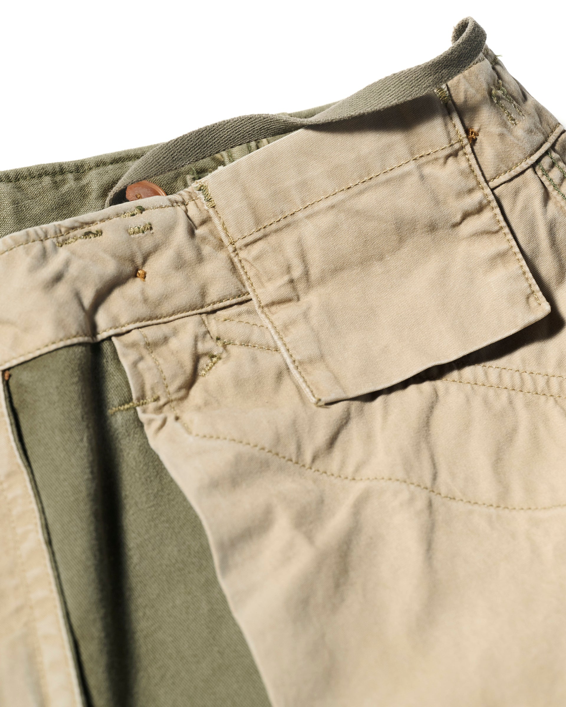 Close-up of the waistband and fly of T7C’s The Brando Cargo in Olive Drab, highlighting stitching, buttonhole, and inner green lining.