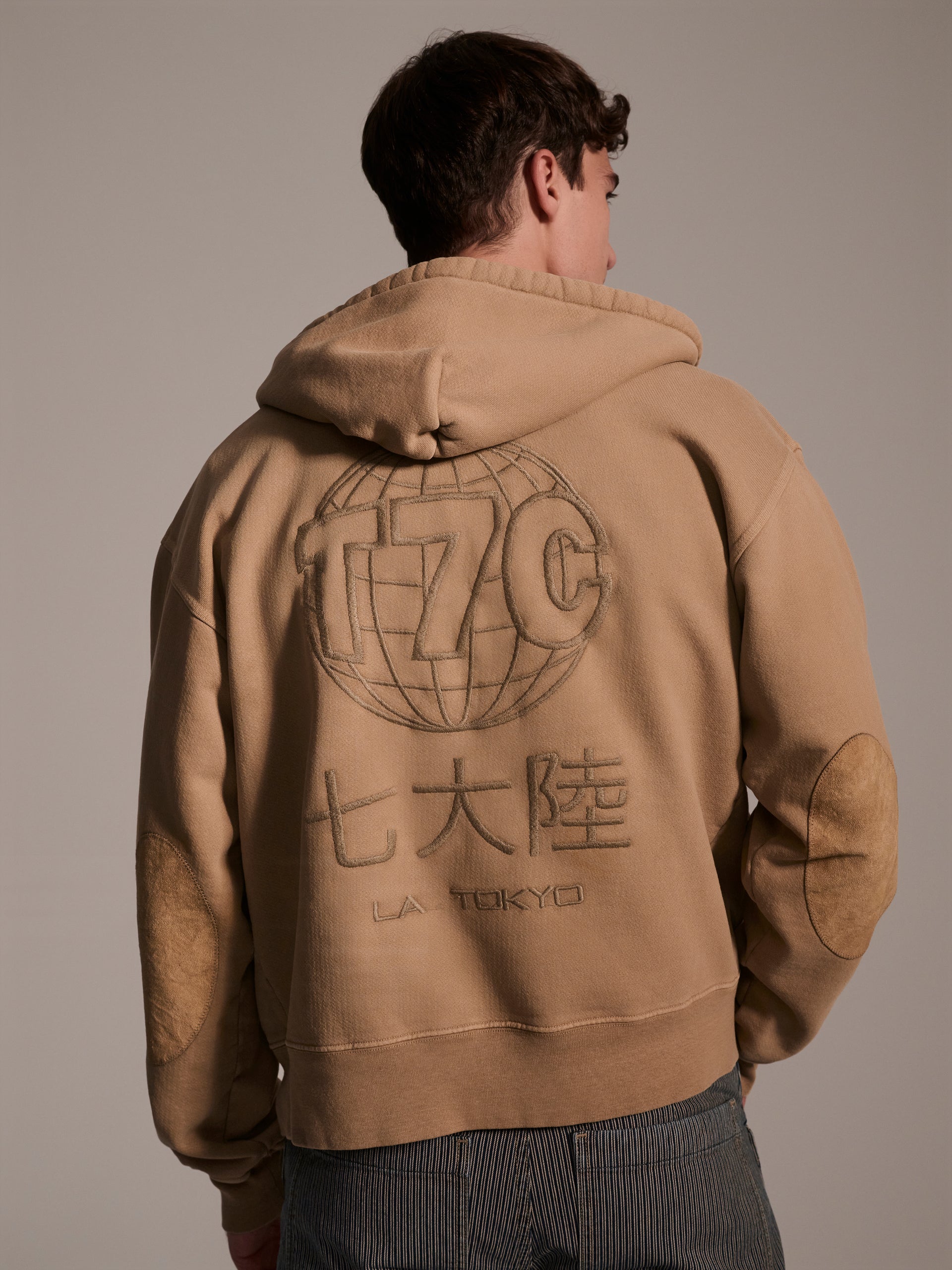 A back image of a male model wearing a tan hoodie