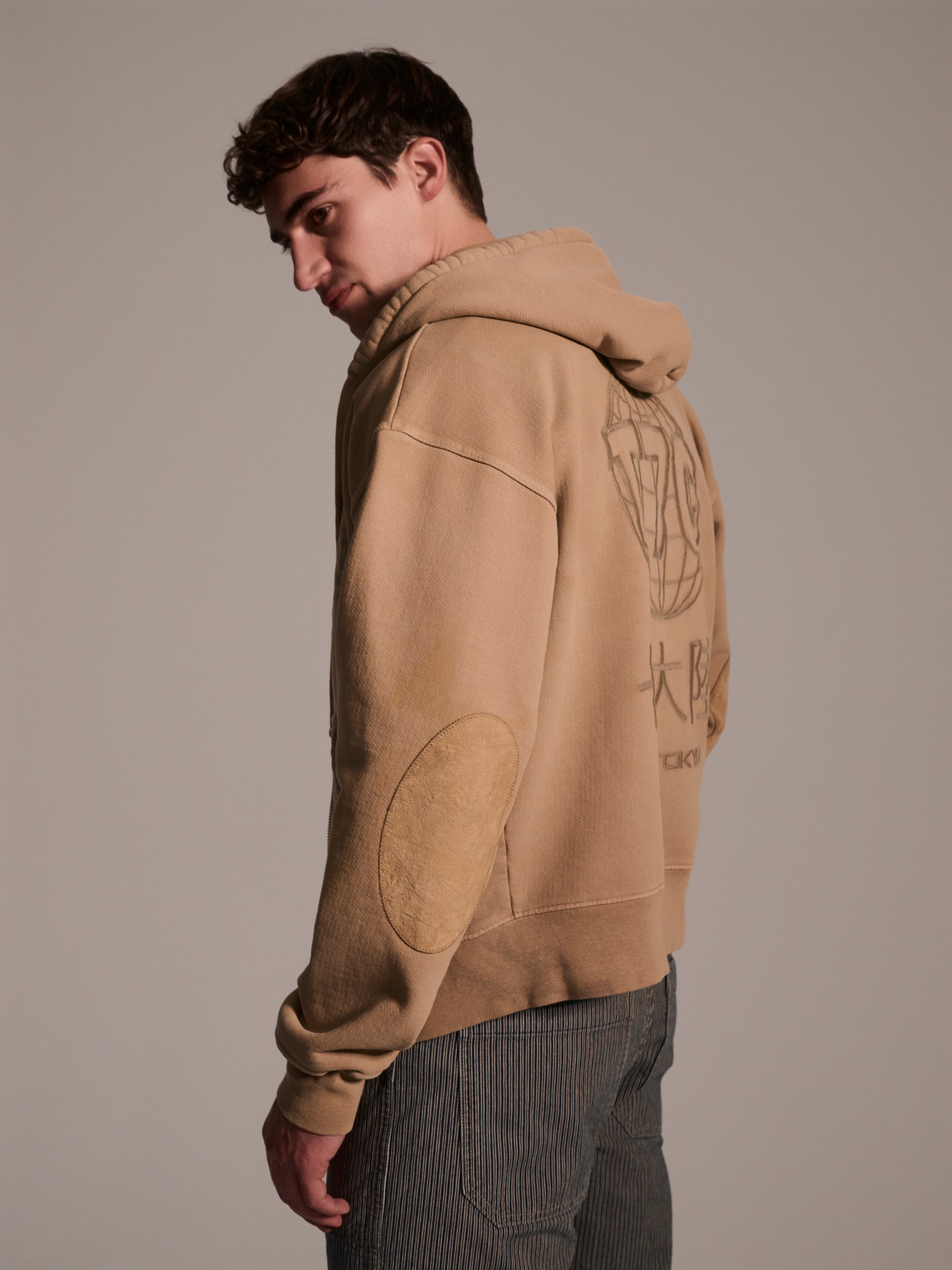 A profile image of male model wearing a tan hoodie 