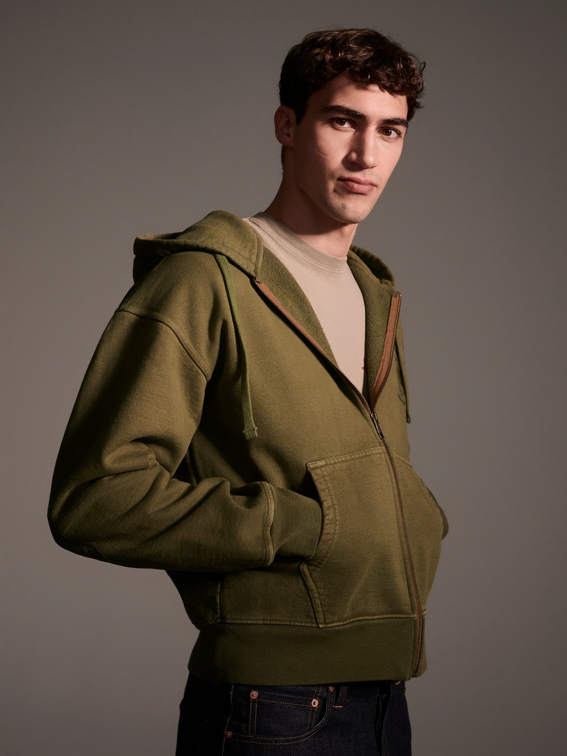 A profile image of a male model in an olive zip-up hoodie