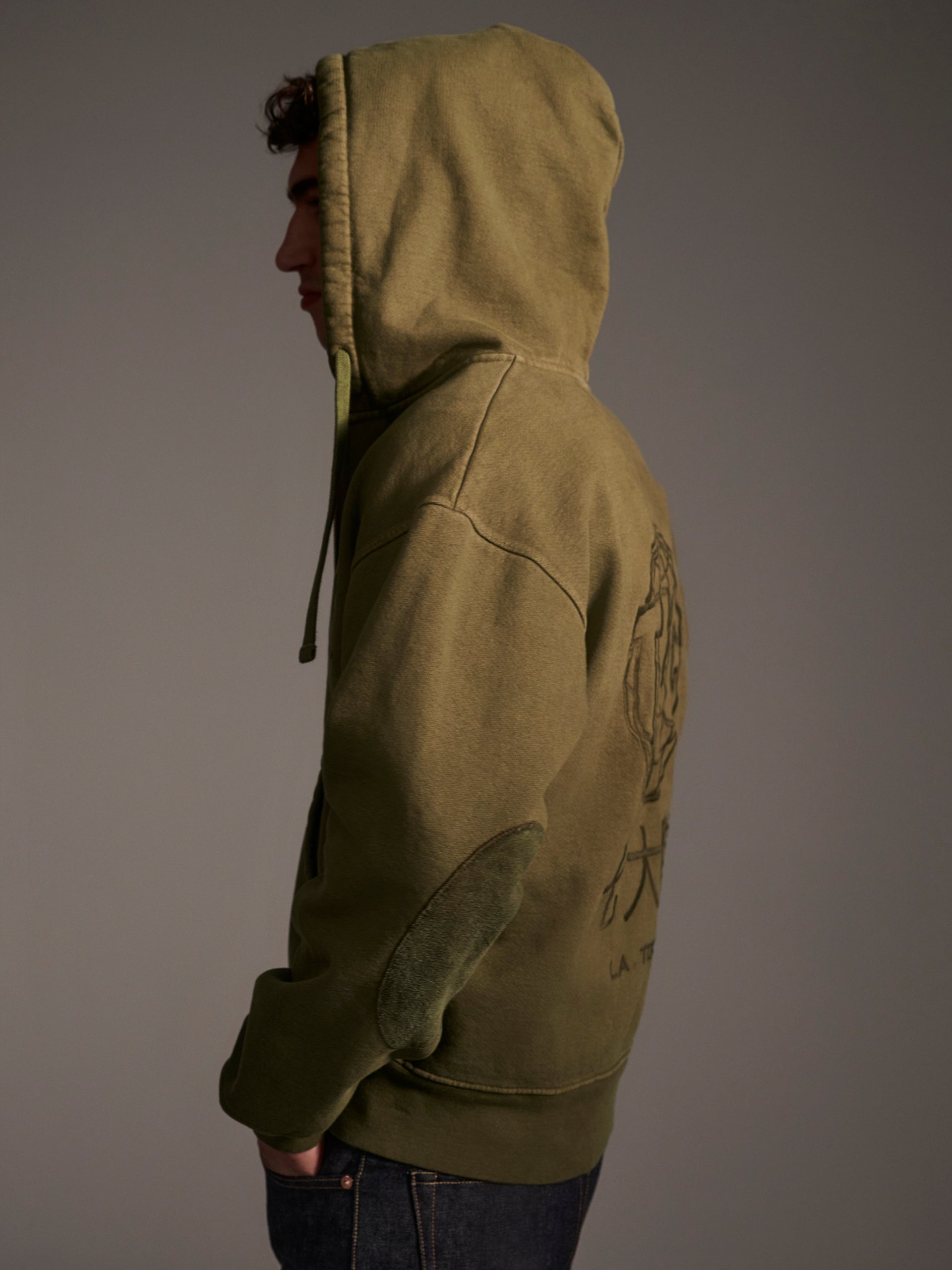 A profille image of a male model in an olive zip-up hoodie