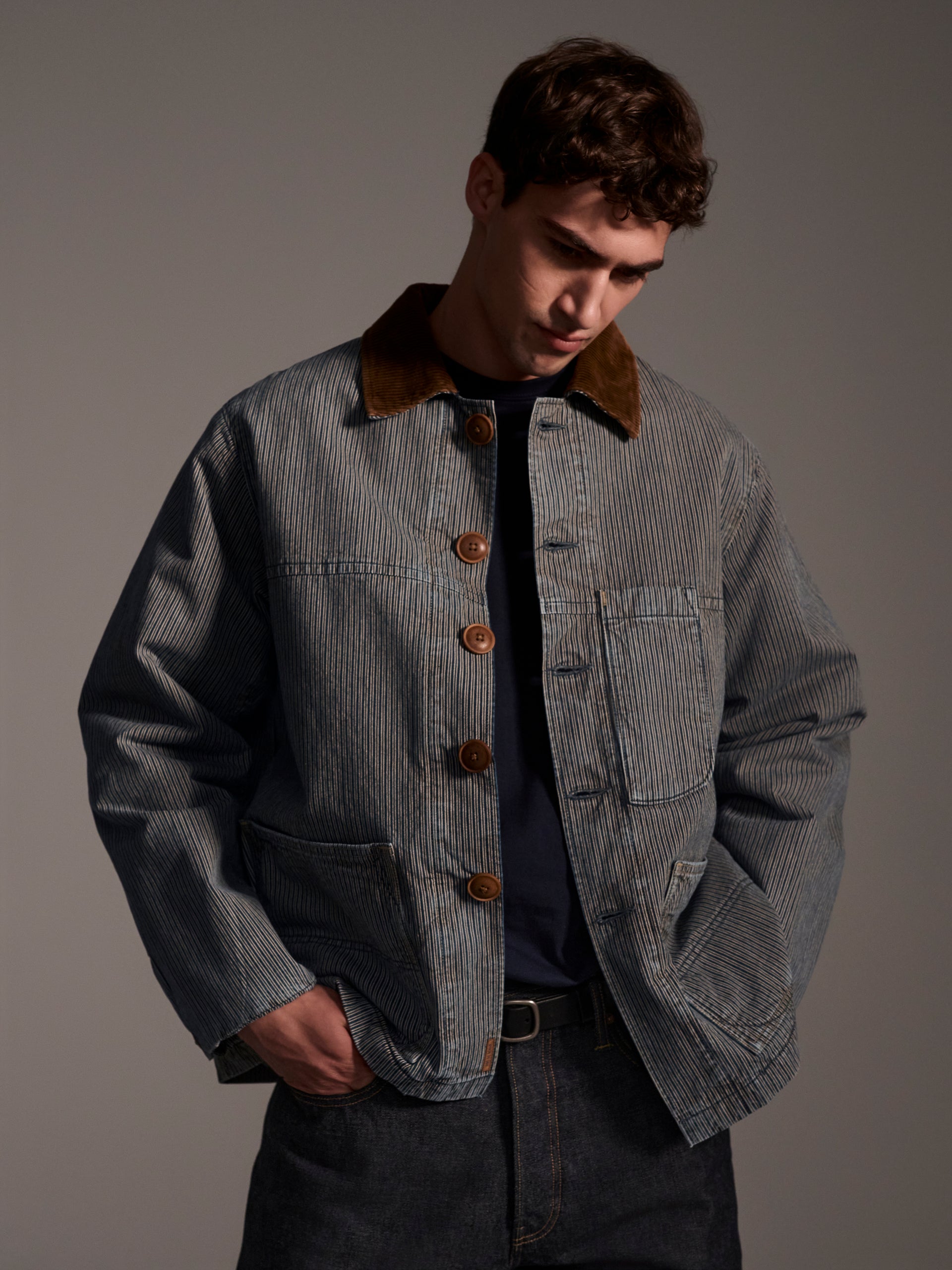 A front image of a male model wearing a blue and white railroad stripe jacket with a corduroy collar