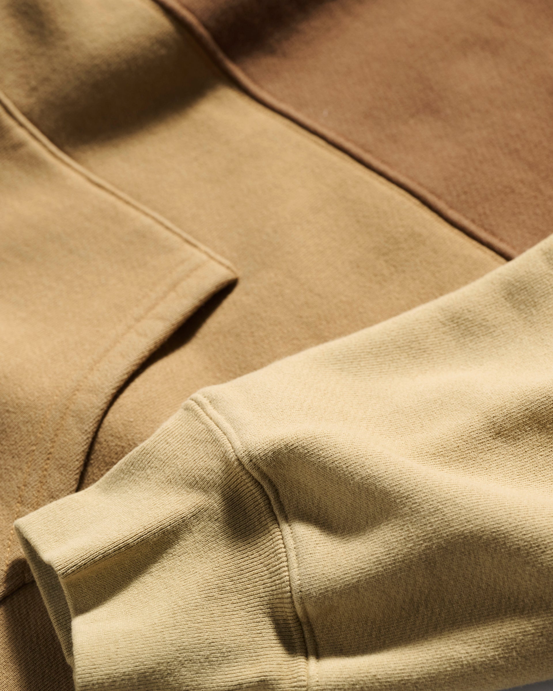 Close-up of the T7C The Seven Continents Hunter Hoodie in Terra, highlighting the fabric texture, a camo-inspired seam, and the sleeve edge in neutral tones.