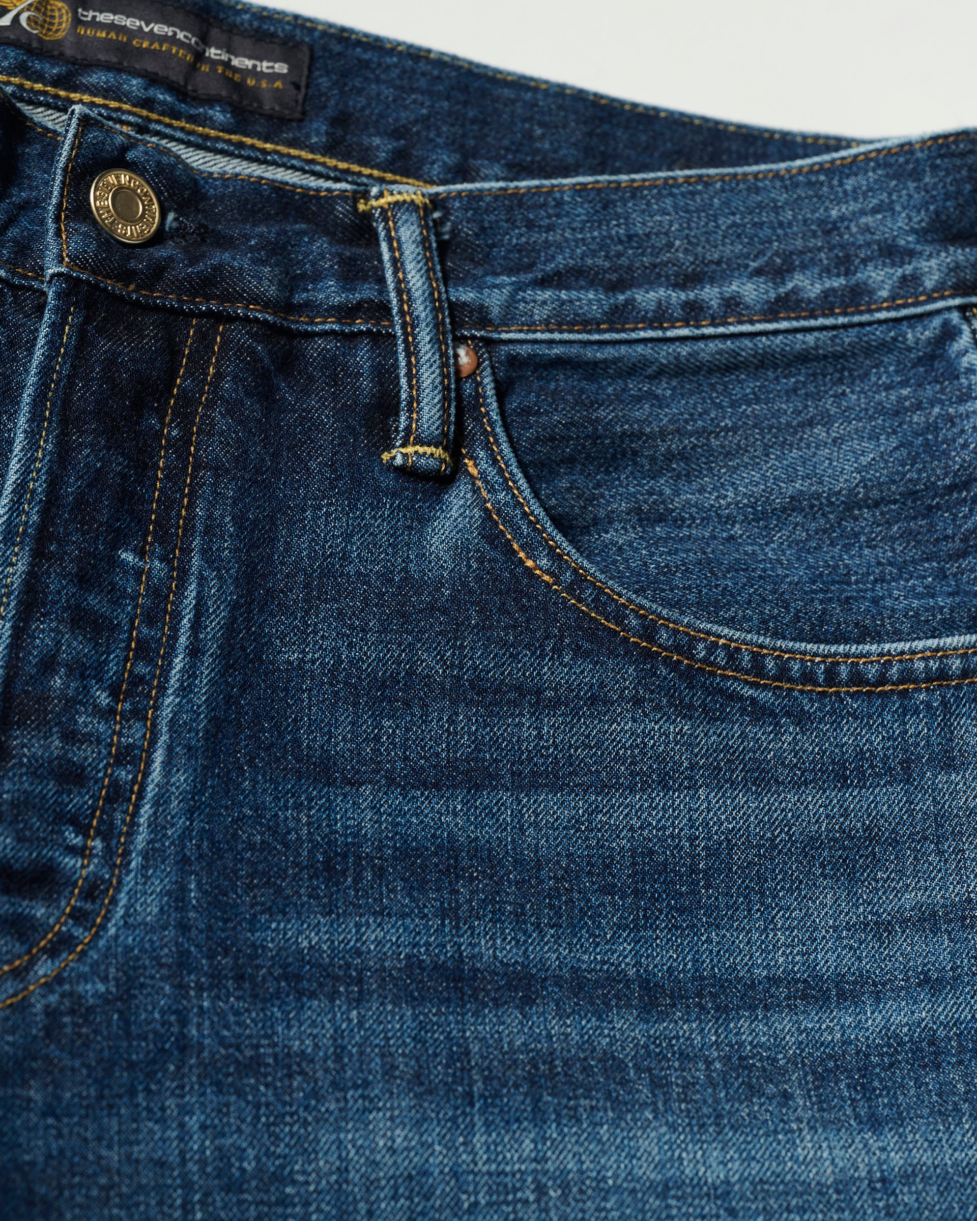 Close-up of the front pocket and waistband of The Jack Jean in Tokyo Medium by T7C, highlighting its metal button, belt loop, coin pocket, and stitching that showcase the vintage texture and craftsmanship of Japanese denim.