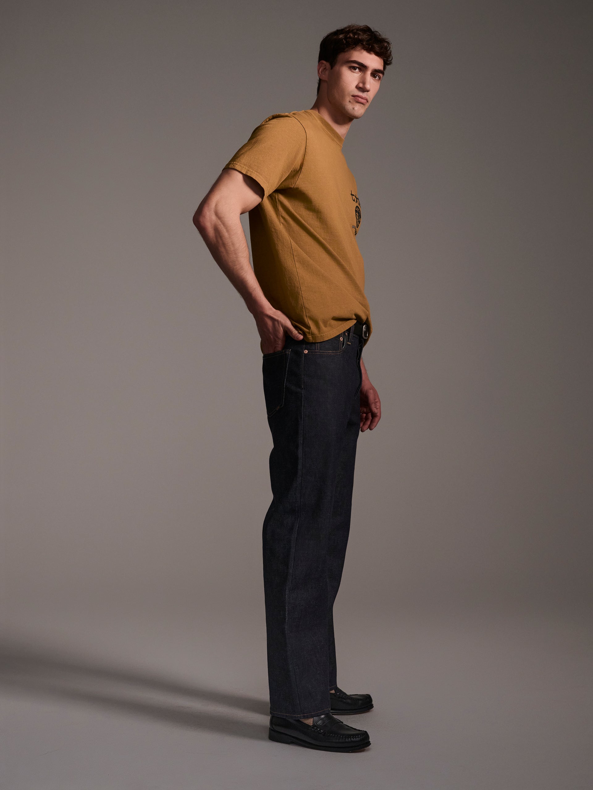 A profile image of a male model wearing dark blue relaxed fit raw denim jeans