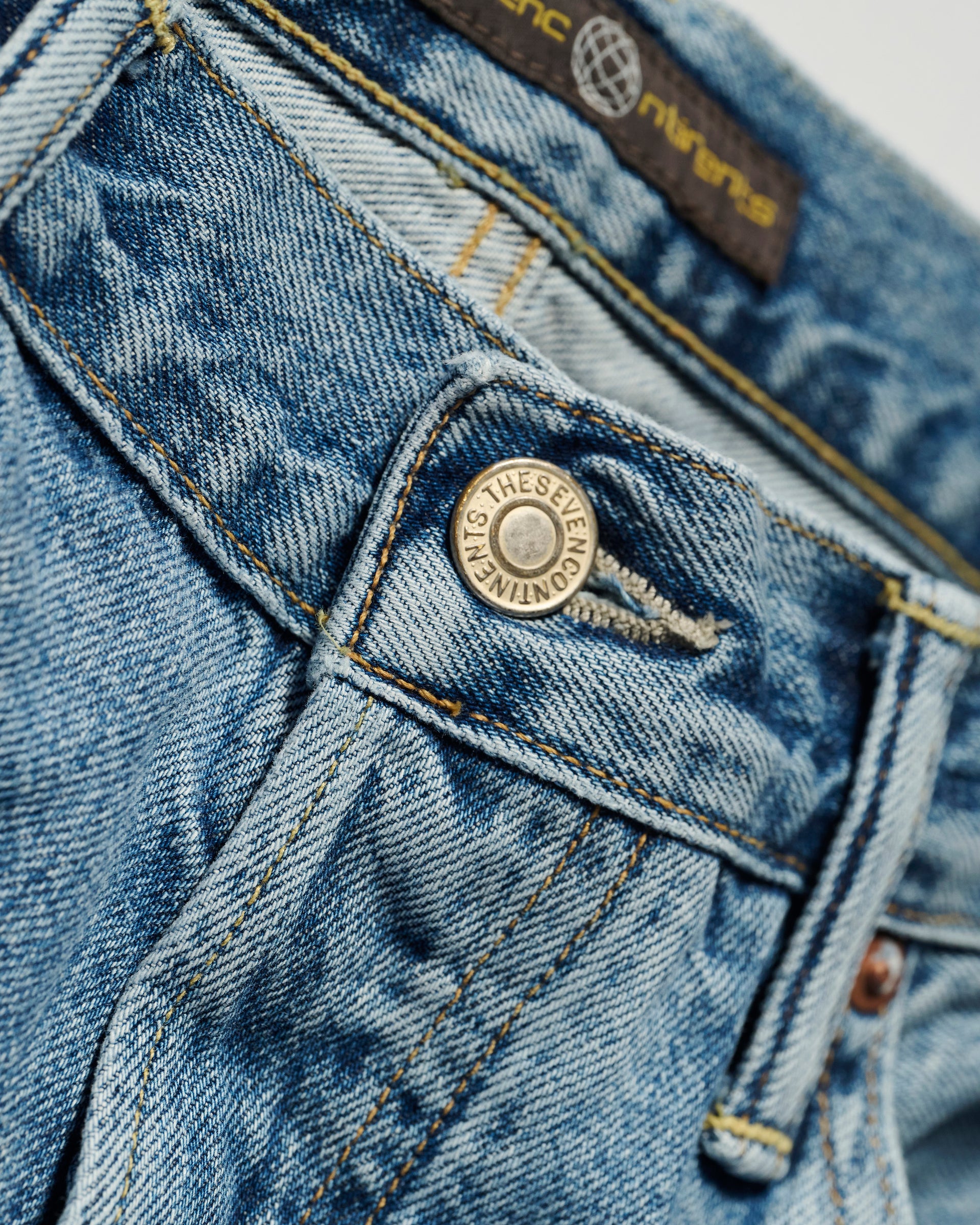 Close-up of The Jack Jean in Zuma by T7C The Seven Continents, highlighting the front pocket, button, belt loop, visible stitching, and a partially visible label at the waistband.