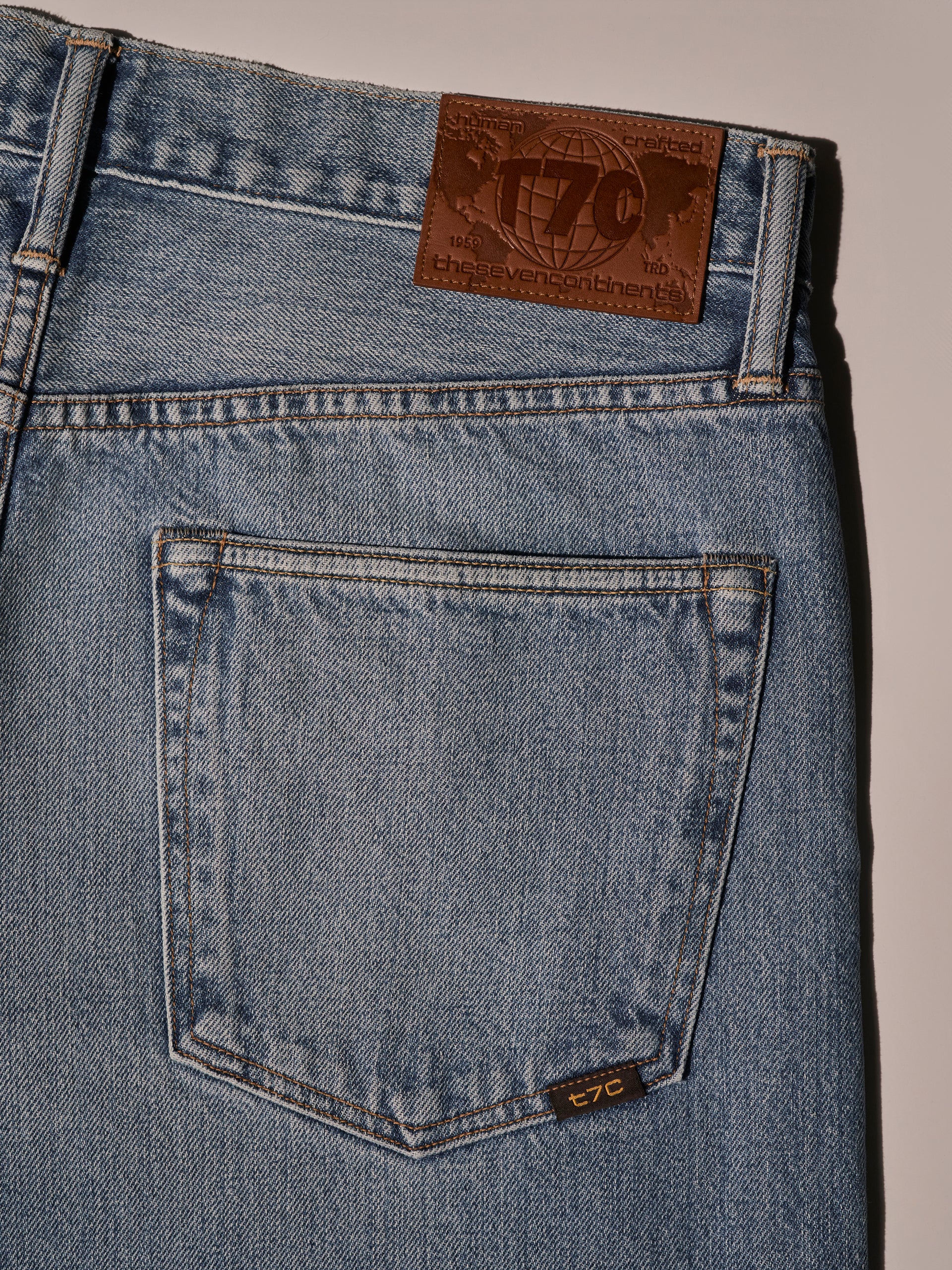 A flay lay image of light blue denim jean with a brown back patch