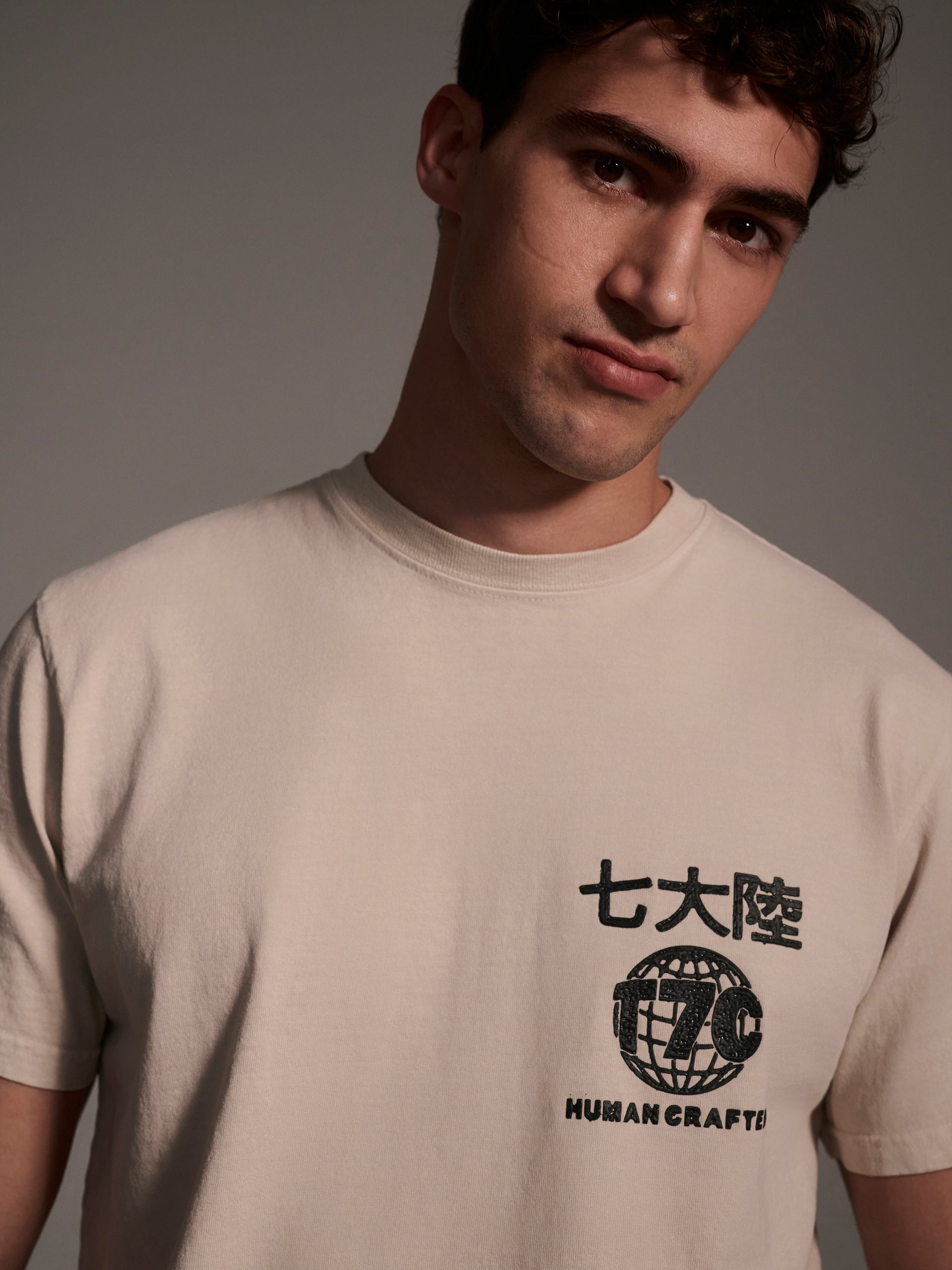 A detail image of a male model wearing an off-white t-shirt with a logo detail