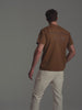 A video of a male model wearing a brown t-shirt with a logo detail